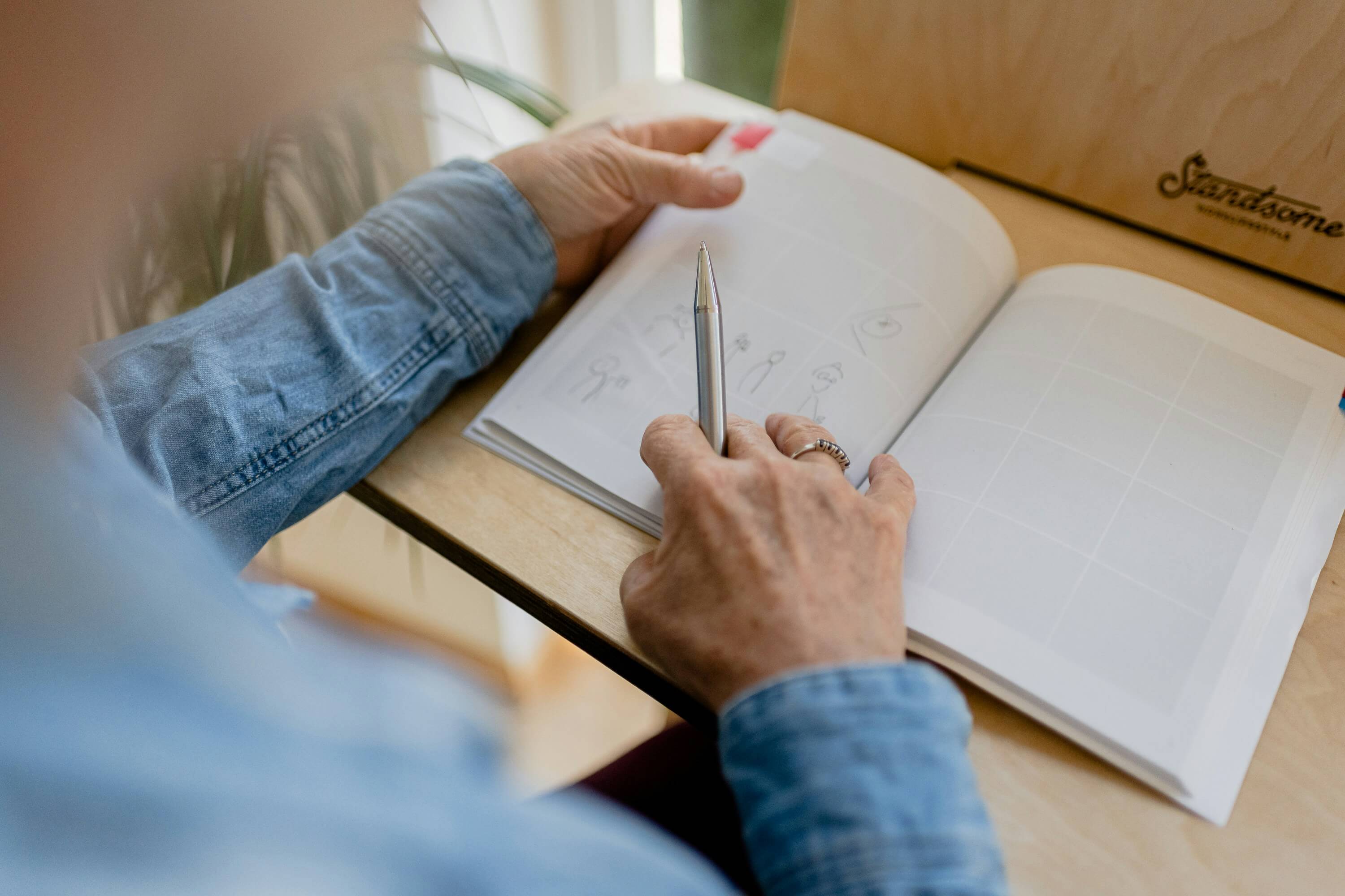 Hands holding a pen and notebook on a desk